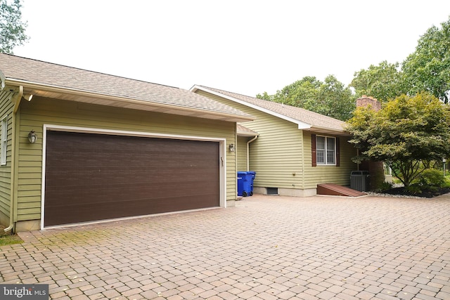 view of property exterior with central air condition unit and a garage