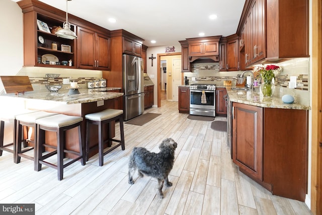 kitchen featuring decorative light fixtures, stainless steel appliances, light wood-type flooring, and decorative backsplash