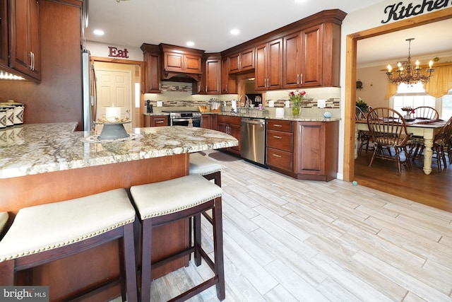 kitchen featuring light hardwood / wood-style floors, light stone countertops, stainless steel appliances, kitchen peninsula, and hanging light fixtures