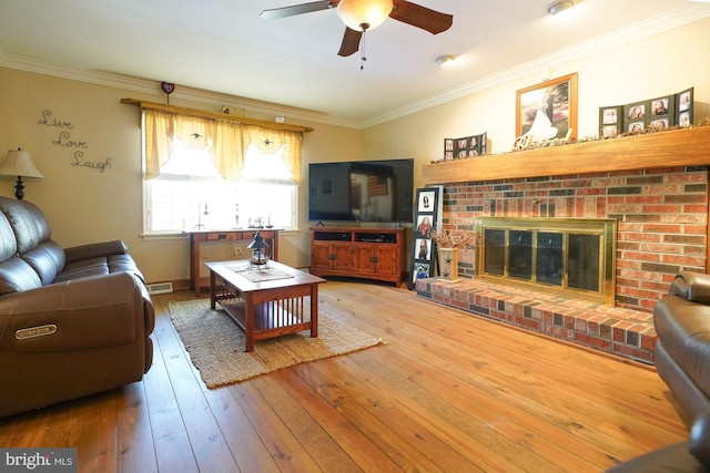 living room featuring ceiling fan, hardwood / wood-style flooring, a fireplace, and ornamental molding