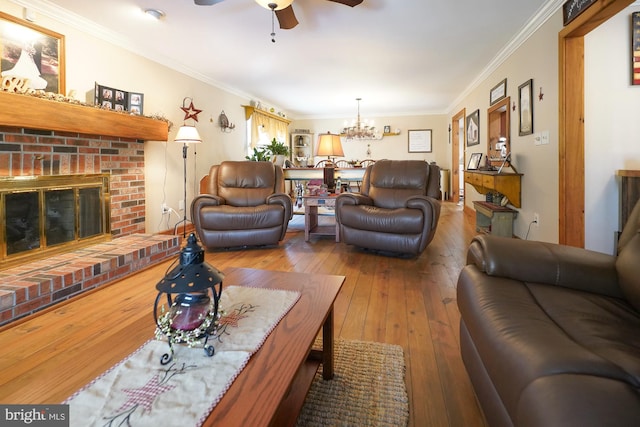 living room featuring a fireplace, ceiling fan with notable chandelier, crown molding, and hardwood / wood-style flooring