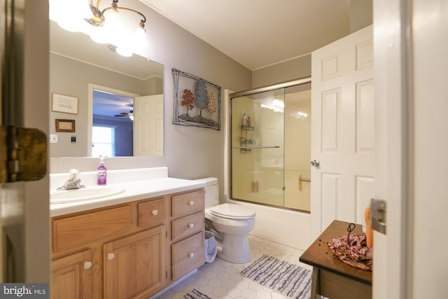 full bathroom featuring ceiling fan, shower / bath combination with glass door, vanity, toilet, and tile patterned flooring