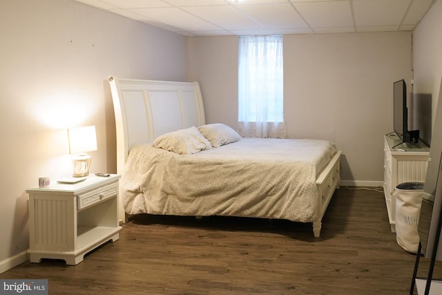 bedroom with a drop ceiling and dark hardwood / wood-style flooring