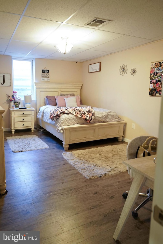 bedroom with a drop ceiling and hardwood / wood-style flooring