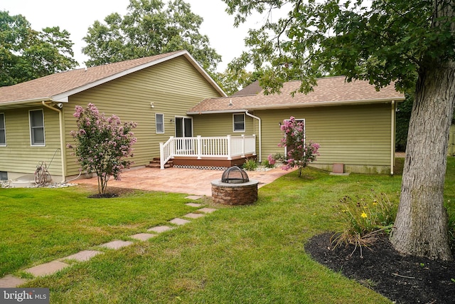 rear view of house with a wooden deck, a yard, a patio area, and an outdoor fire pit