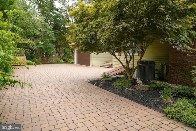 view of patio featuring central air condition unit and a garage