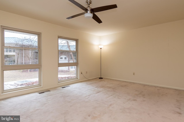 unfurnished room with baseboards, visible vents, a ceiling fan, and light colored carpet