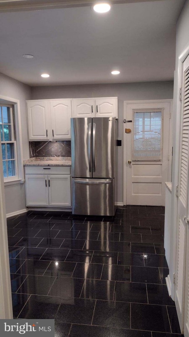 kitchen with white cabinetry, stainless steel refrigerator, and tasteful backsplash