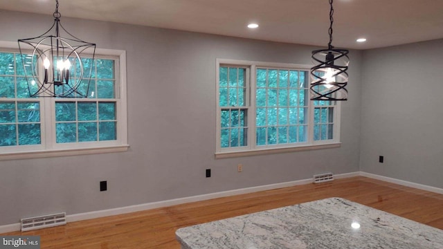 unfurnished dining area with a chandelier and light wood-type flooring