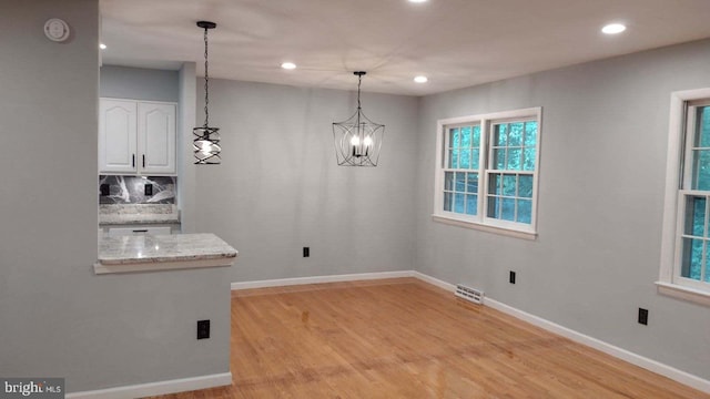 unfurnished dining area featuring a notable chandelier and light wood-type flooring