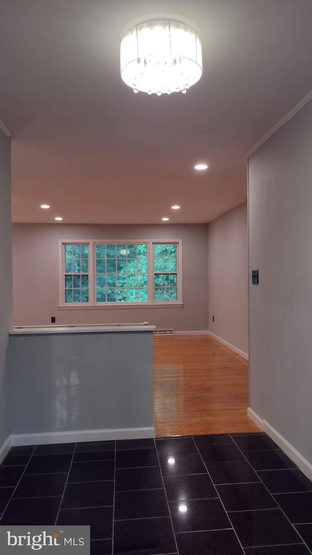 spare room with dark tile patterned floors and ornamental molding