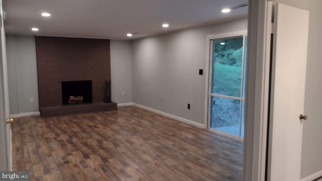 basement with a brick fireplace and dark wood-type flooring