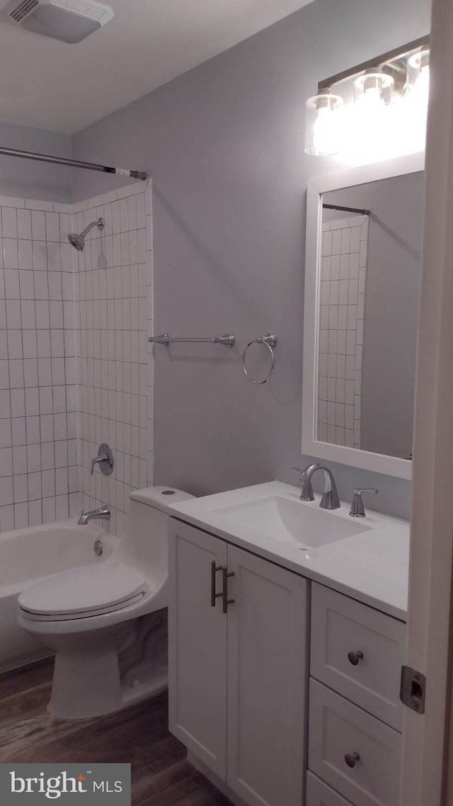 full bathroom featuring toilet, hardwood / wood-style floors, vanity, and tiled shower / bath