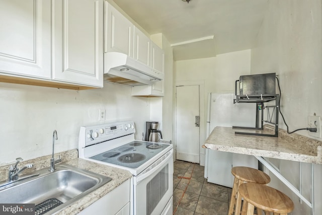 kitchen featuring dark tile patterned flooring, sink, white cabinetry, a breakfast bar, and white range with electric cooktop