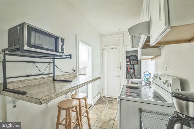 kitchen with white cabinets, kitchen peninsula, a breakfast bar area, washer / dryer, and sink