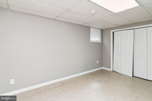 unfurnished bedroom featuring a closet, light tile patterned floors, and a paneled ceiling