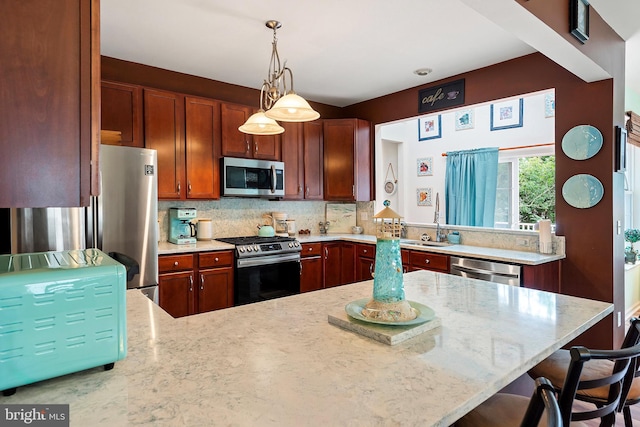 kitchen with a kitchen breakfast bar, hanging light fixtures, decorative backsplash, stainless steel appliances, and sink