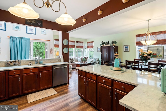 kitchen with dishwasher, hardwood / wood-style flooring, sink, decorative light fixtures, and light stone countertops