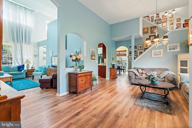 living room featuring an inviting chandelier, light wood-type flooring, and a towering ceiling