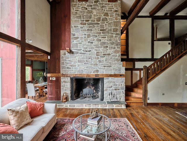 living room featuring a high ceiling, a fireplace, beamed ceiling, and hardwood / wood-style flooring