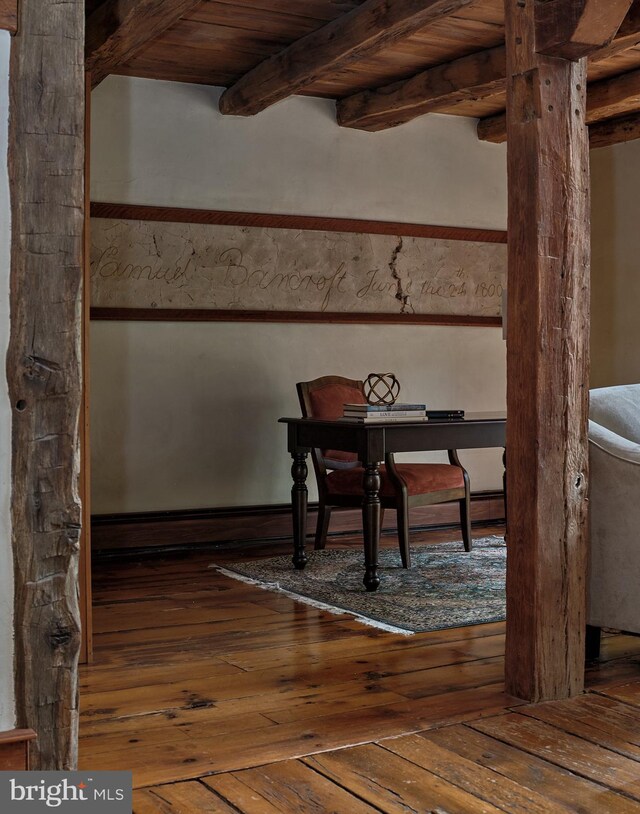 unfurnished dining area featuring wood-type flooring, beamed ceiling, and wooden ceiling