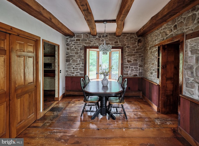 dining space with wood walls, beamed ceiling, a chandelier, and dark wood-type flooring