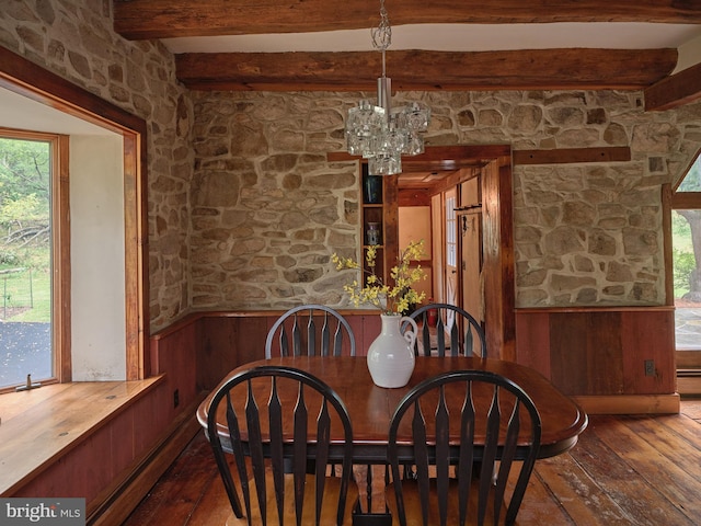 dining area with wood-type flooring, beamed ceiling, wood walls, and an inviting chandelier