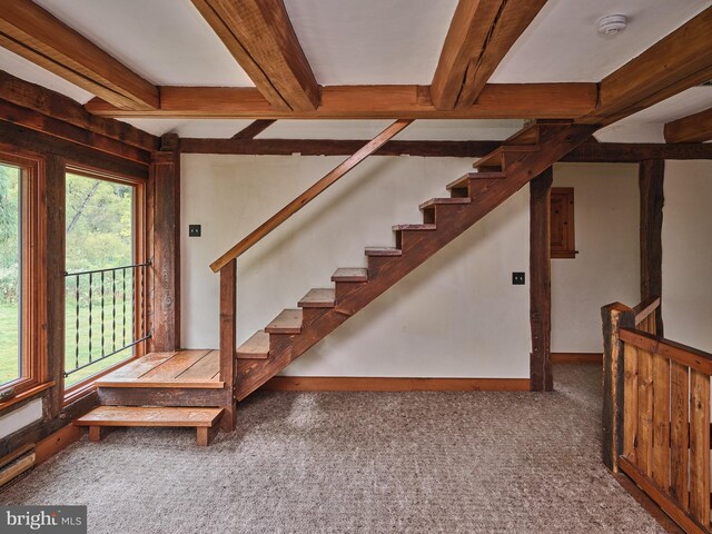 stairway with carpet and beamed ceiling