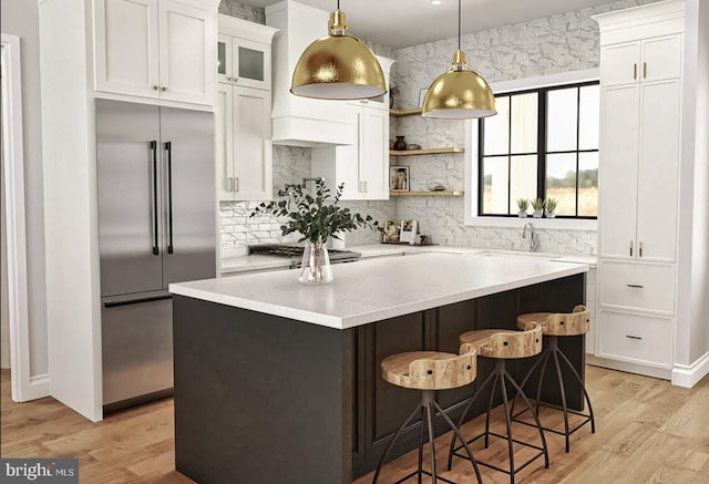 kitchen with appliances with stainless steel finishes, light hardwood / wood-style floors, a kitchen island, and white cabinets