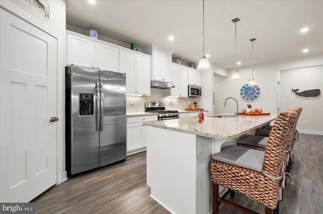 kitchen featuring sink, decorative light fixtures, a kitchen island with sink, stainless steel appliances, and dark hardwood / wood-style floors