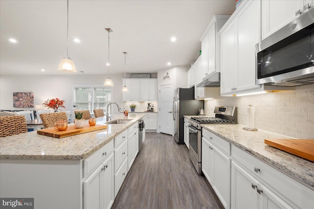 kitchen featuring stainless steel appliances, white cabinets, a kitchen island with sink, and sink