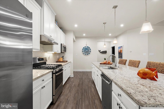 kitchen featuring sink, white cabinets, hanging light fixtures, stainless steel appliances, and a center island with sink