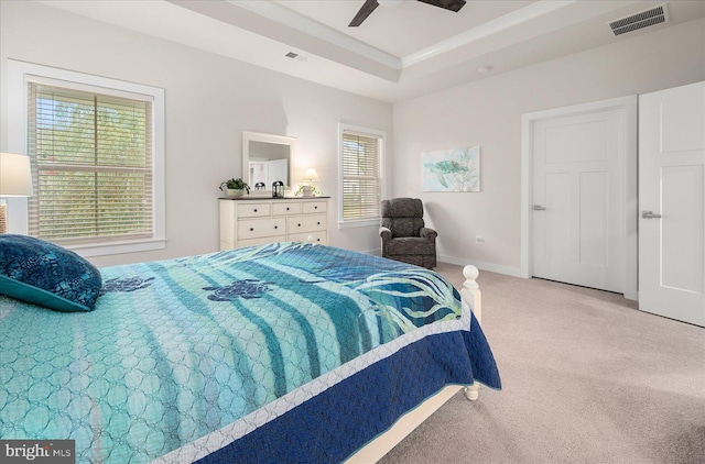 carpeted bedroom with ceiling fan and a raised ceiling