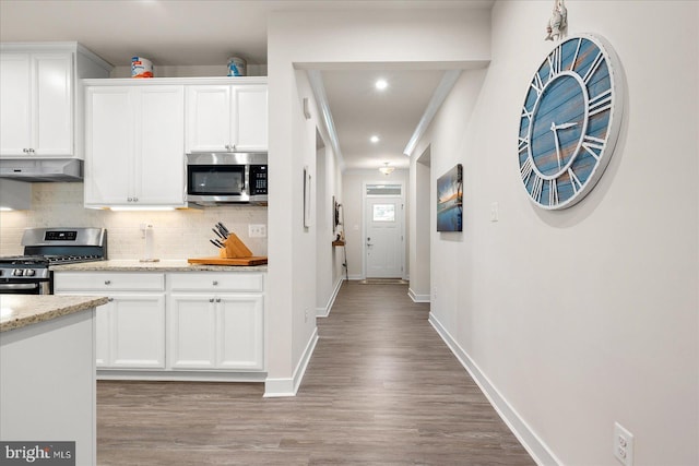 kitchen featuring light stone counters, white cabinets, stainless steel appliances, and light hardwood / wood-style floors