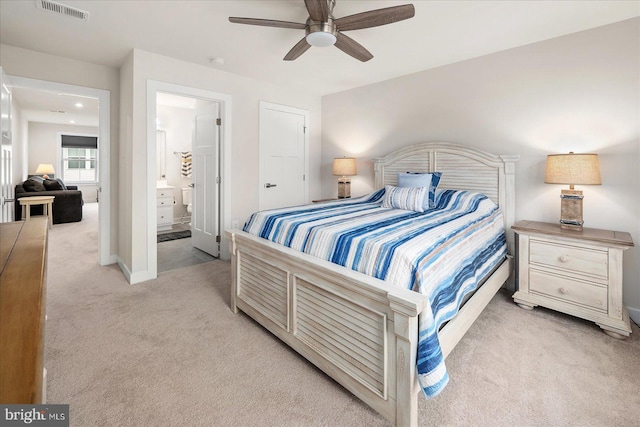 bedroom with ceiling fan, ensuite bath, and light carpet