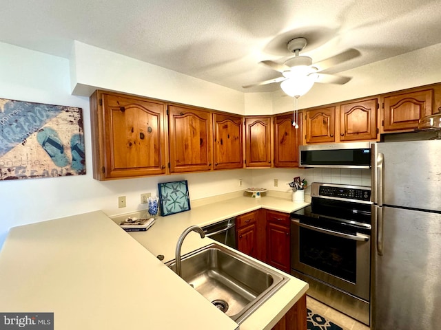 kitchen with ceiling fan, sink, a textured ceiling, backsplash, and stainless steel appliances