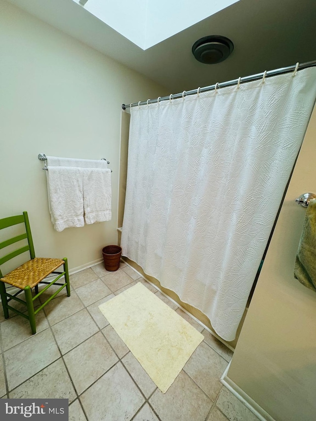 bathroom with tile patterned flooring, a skylight, and curtained shower