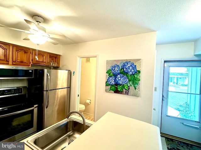 38421 Cardinal Ln Unit 195, Selbyville, DE 19975 - kitchen featuring a sink, a ceiling fan, a textured ceiling, brown cabinets, and stainless steel appliances