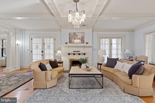 living room featuring an inviting chandelier, french doors, a brick fireplace, light hardwood / wood-style flooring, and radiator heating unit