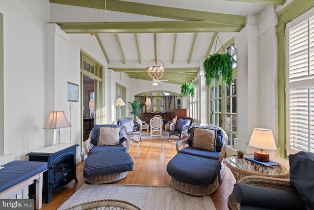 sunroom featuring lofted ceiling with beams and ceiling fan with notable chandelier