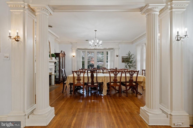 dining space with hardwood / wood-style floors, ornate columns, crown molding, and a chandelier