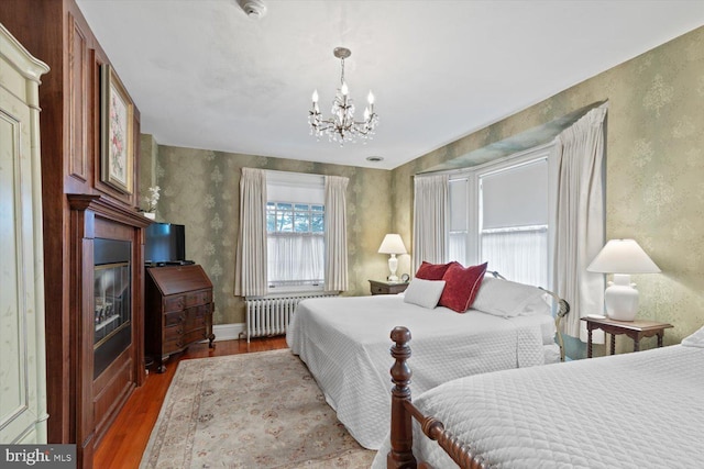 bedroom featuring wood-type flooring, an inviting chandelier, and radiator