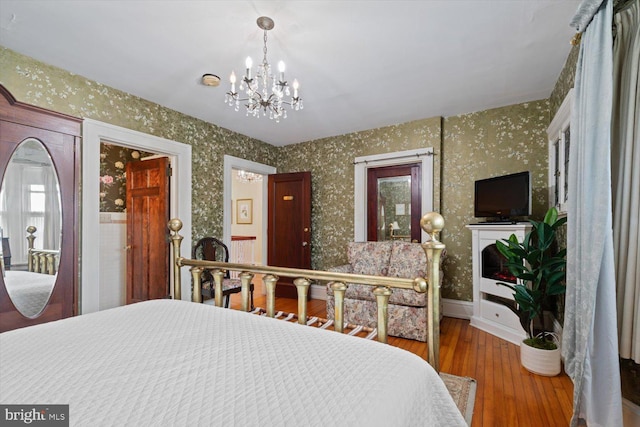 bedroom with hardwood / wood-style floors and a notable chandelier