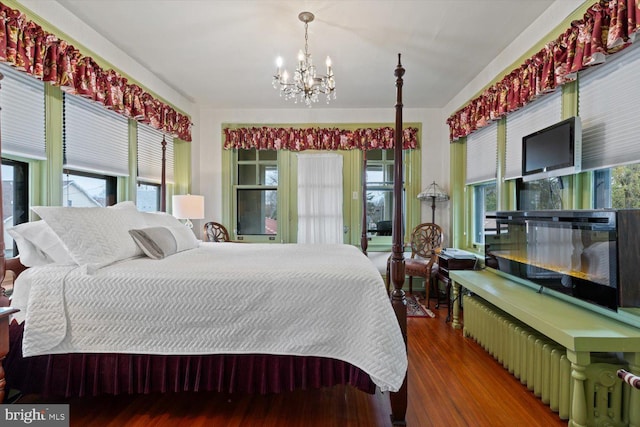 bedroom featuring multiple windows, hardwood / wood-style floors, and a notable chandelier