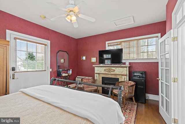 bedroom featuring hardwood / wood-style floors, ceiling fan, and a fireplace