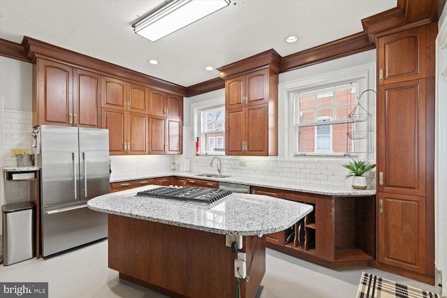 kitchen with sink, light stone countertops, tasteful backsplash, a kitchen island, and stainless steel appliances