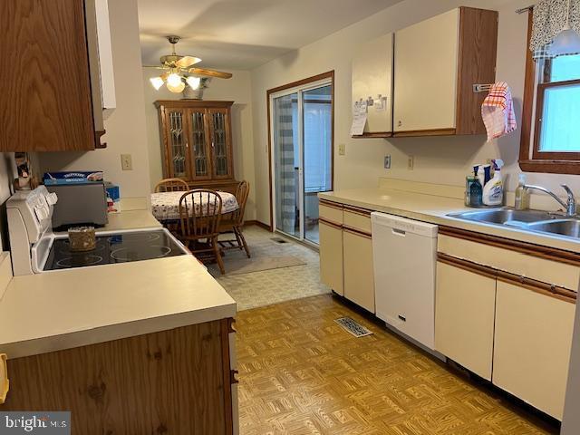 kitchen with dishwasher, sink, white cabinets, black range, and ceiling fan