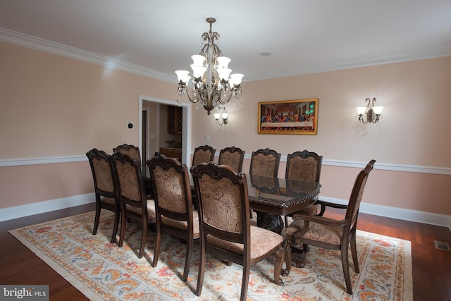 dining room featuring dark hardwood / wood-style flooring, crown molding, and a notable chandelier