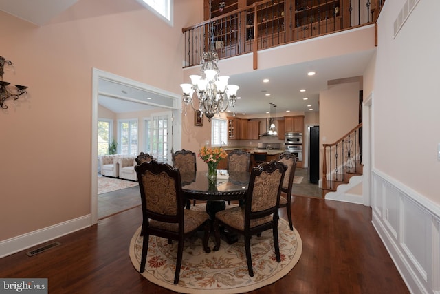 dining room with a chandelier, a towering ceiling, and dark wood-type flooring