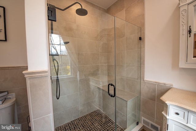 bathroom with walk in shower, vanity, toilet, and tile walls